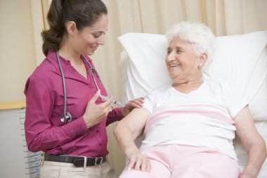 Doctor giving needle to woman in exam room smiling clipart