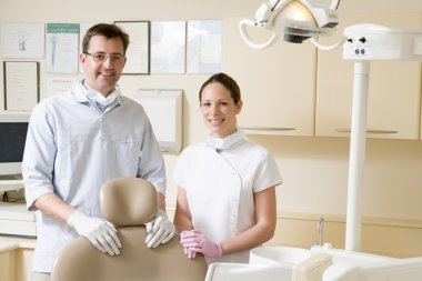 Dentist and assistant in exam room smiling clipart