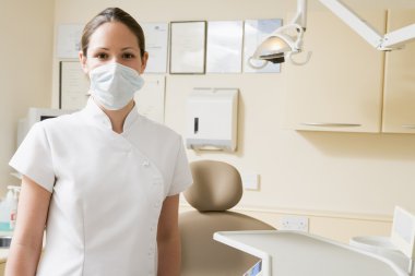 Dental assistant in exam room with mask on clipart