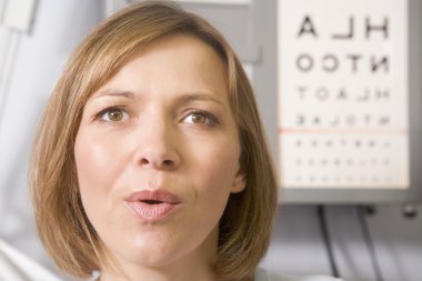 Woman in optometrist's exam room taking deep breath clipart