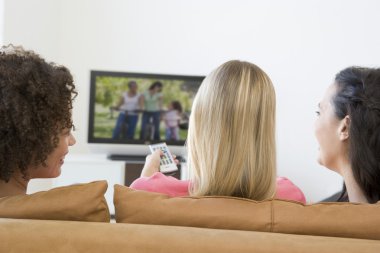 Three women in living room watching television clipart