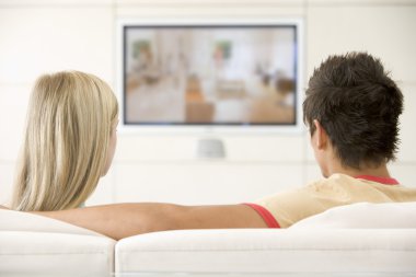 Couple in living room watching television clipart