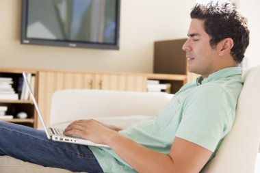 Man in living room using laptop clipart