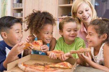 Four young children indoors with woman eating pizza smiling clipart