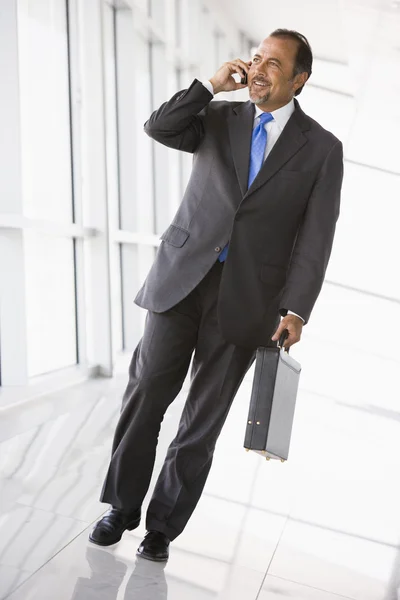 Бизнесмен разговаривает по мобильному телефону в холле — стоковое фото