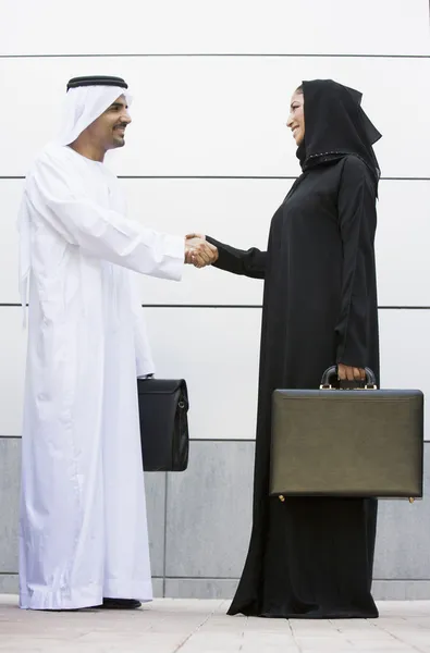 Um empresário e mulher do Oriente Médio apertando as mãos — Fotografia de Stock