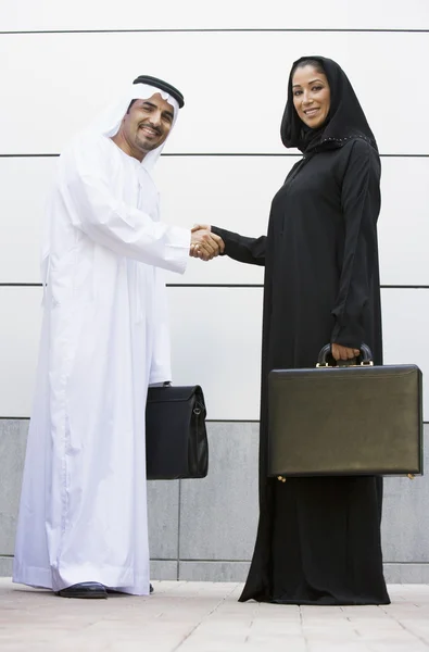 Um empresário e mulher do Oriente Médio apertando as mãos — Fotografia de Stock