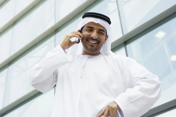 A Middle Eastern businessman talking on the phone outside an off — Stock Photo, Image