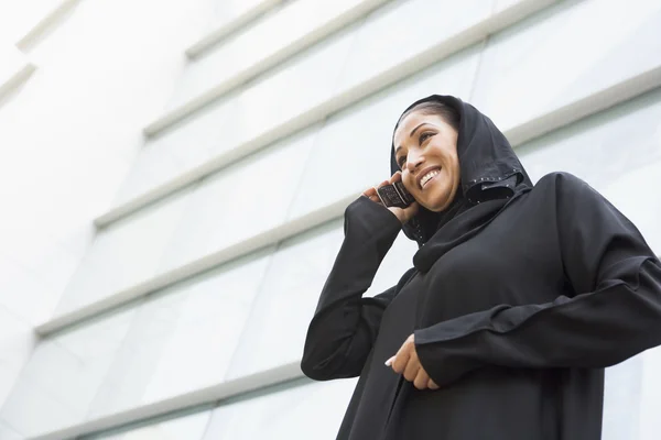 A Middle Eastern businesswoman talking on the phone outside an o — Stock Photo, Image