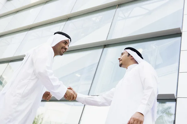 Two Middle Eastern businessmen shaking hands outside an office b — Stock Photo, Image