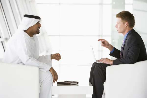 Мужчина с Ближнего Востока и кавказский мужчина разговаривают в бизнес-центре — стоковое фото
