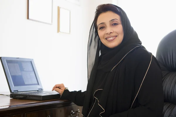 坐在家里的电脑前, 一个中东女人 — 图库照片