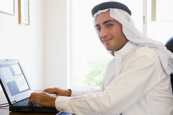Un hombre de Oriente Medio sentado frente a una computadora en casa —  Fotos de Stock