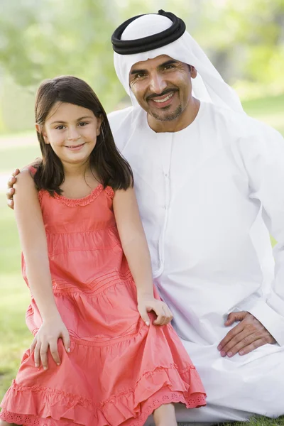 A Middle Eastern man and his daughter sitting in a park — Stock Photo, Image