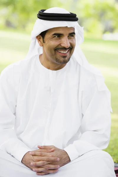 Un uomo mediorientale seduto in un parco — Foto Stock