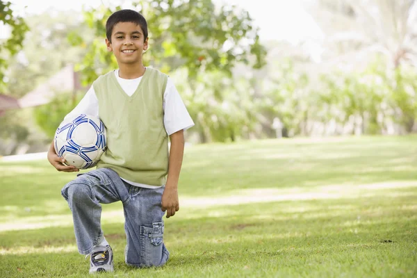Junge im Park hält Fußball — Stockfoto