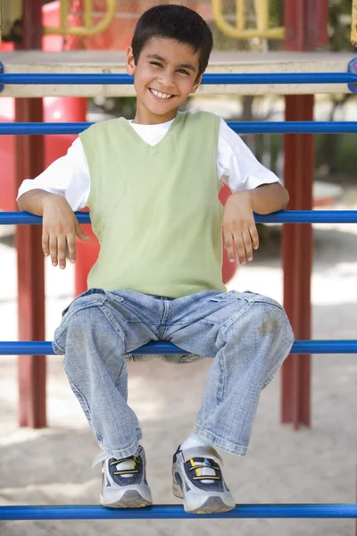 Boy sitting on climbing frame in playground