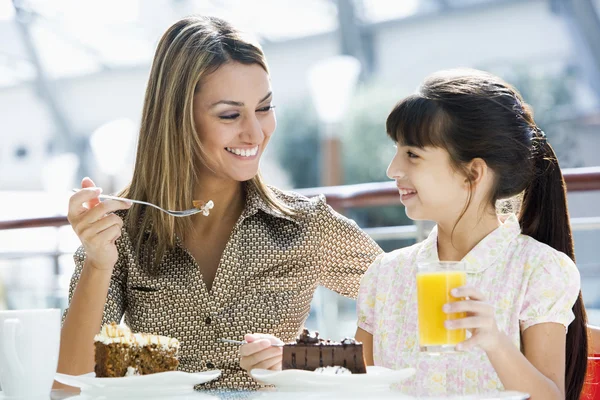 ケーキを食べるとカフェでジュースを飲む母と娘 — ストック写真