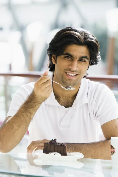 Νεαρός άνδρας τρώει κέικ στο καφέ — Φωτογραφία Αρχείου