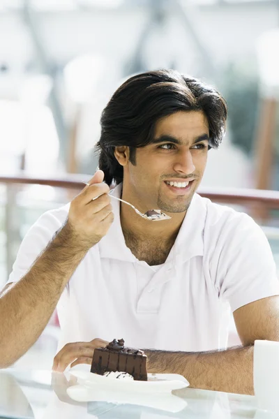 Young man eating cake in cafe — Stock Photo, Image
