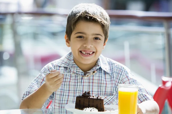 Νεαρό αγόρι που τρώει σοκολάτα κέικ στο καφέ — Φωτογραφία Αρχείου
