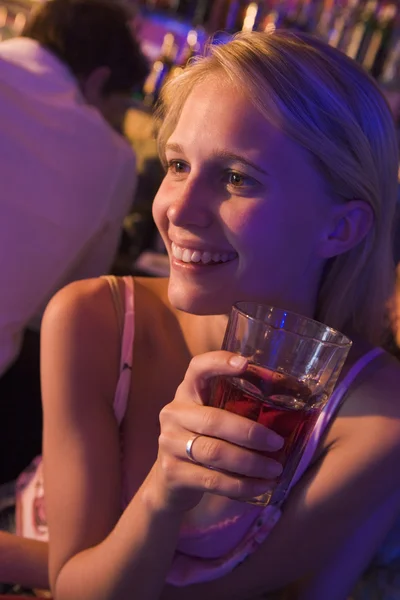 Młoda kobieta pije w nocnym klubie — Zdjęcie stockowe