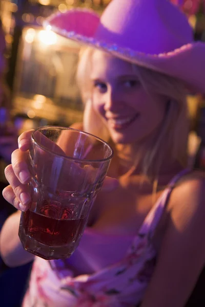 Mladá žena v klubu zvedl nápoj na kameru a s úsměvem — Stock fotografie