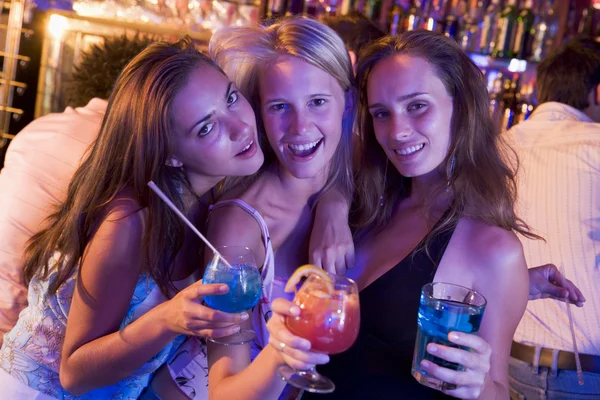 Três jovens mulheres com bebidas em uma boate — Fotografia de Stock