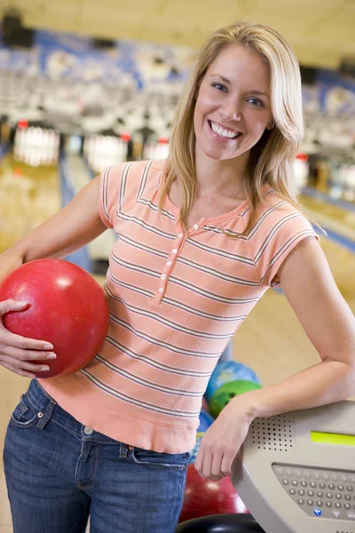 Giovane donna che tiene una palla da bowling in una pista da bowling — Foto Stock