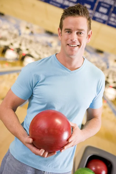 ボーリング場でボーリングのボールを保持している若い男 — ストック写真