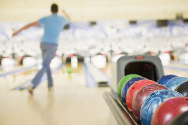 Bowlingové koule stroj s mužem bowling v pozadí — Stock fotografie