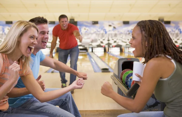 Vier jonge volwassenen juichen in een bowlingbaan — Stockfoto