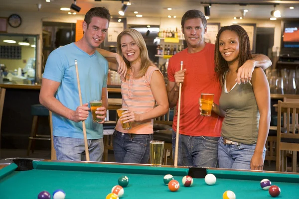 站在酒吧里的台球桌旁边的两个年轻夫妇 — 图库照片