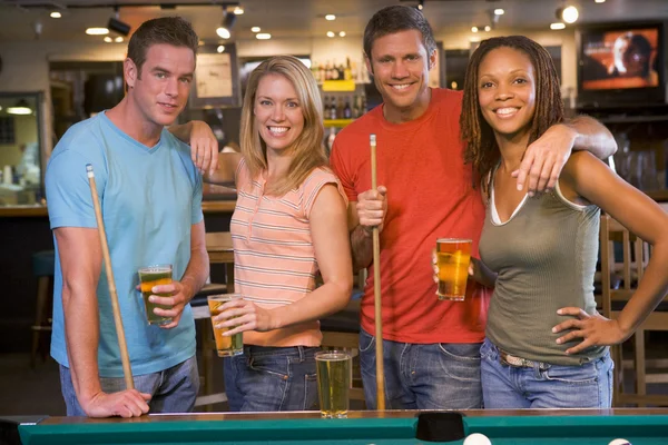 Due giovani coppie in piedi accanto a un tavolo da biliardo in un bar — Foto Stock