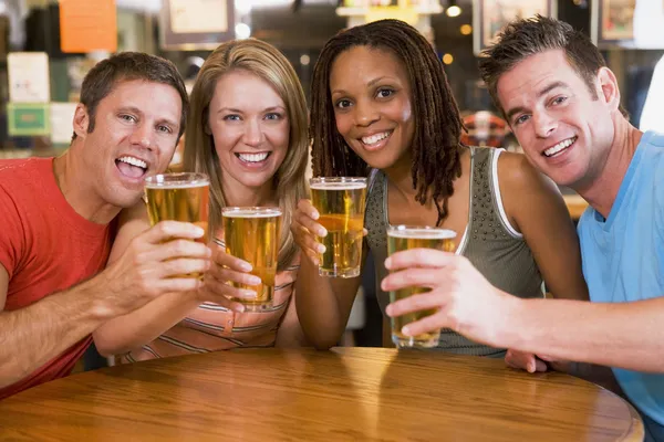 Group of young friends in bar toasting the camera — Stock Photo, Image
