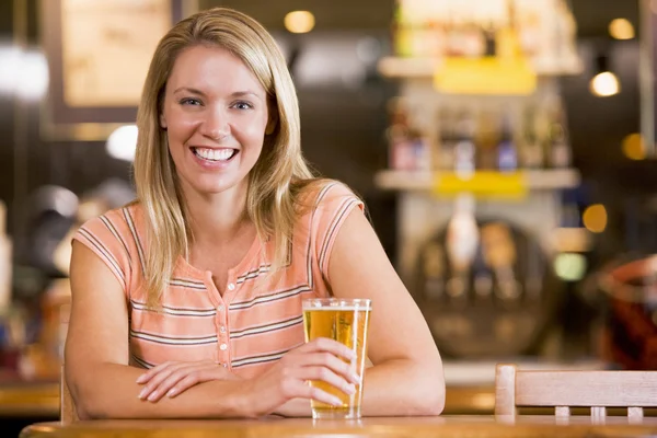 बारमध्ये बिअरचा आनंद घेणारी तरुण स्त्री — स्टॉक फोटो, इमेज