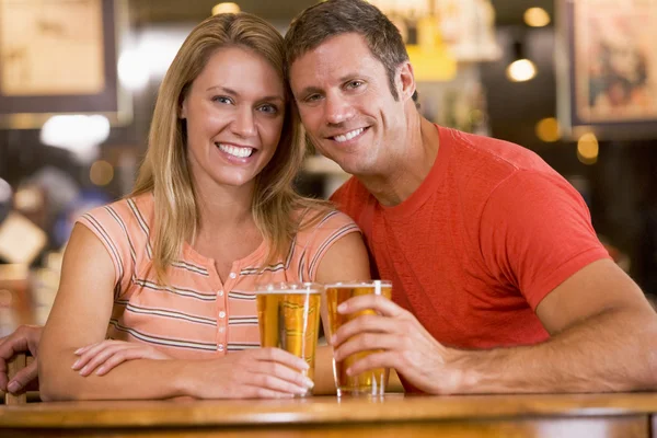Счастливая молодая пара пьет пиво в баре — стоковое фото