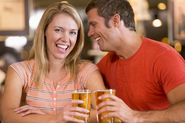 年轻男子在酒吧他的女友耳边低语 — 图库照片