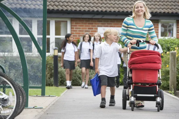 Une femme avec une poussette raccompagnant son fils à la maison depuis l'école — Photo