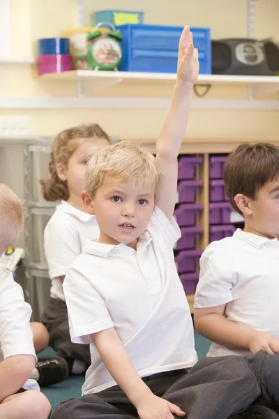 En skolpojke höjer handen i en primär klass — Stockfoto