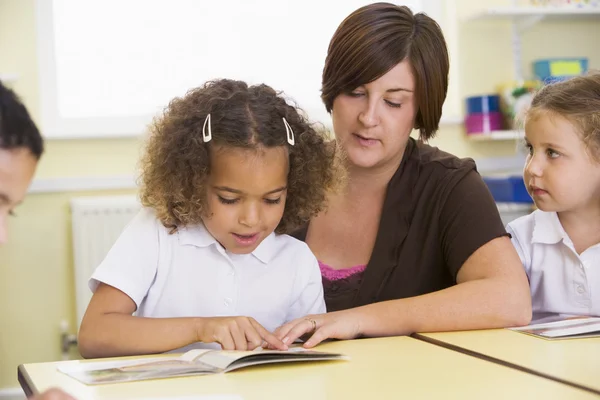 Schoolkinderen en hun leraar lezen in een primaire klasse — Stockfoto