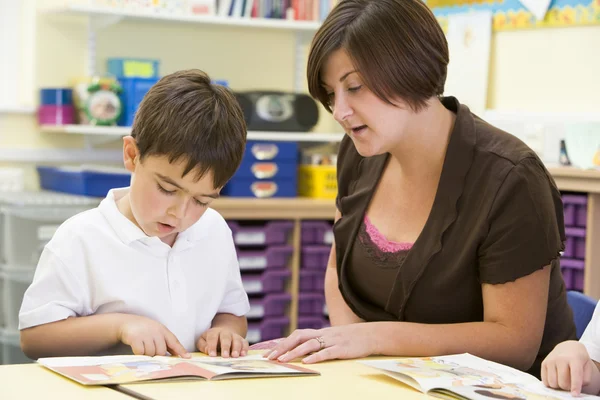 Een schooljongen en zijn leraar lezen in een primaire klasse — Stockfoto