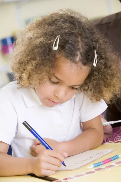 Flicka lära sig att skriva siffror i primära klass — Stockfoto