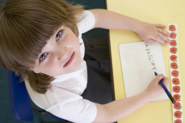 Девочка учится писать числа в начальном классе — стоковое фото