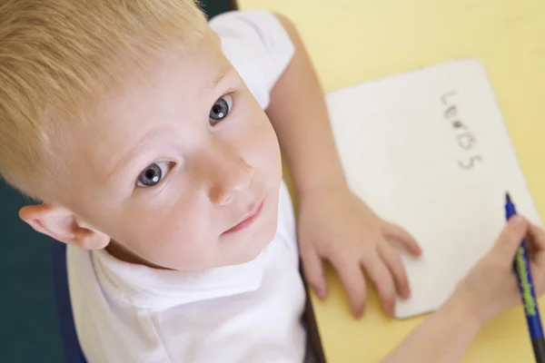 Мальчик учится писать имя в начальном классе — стоковое фото