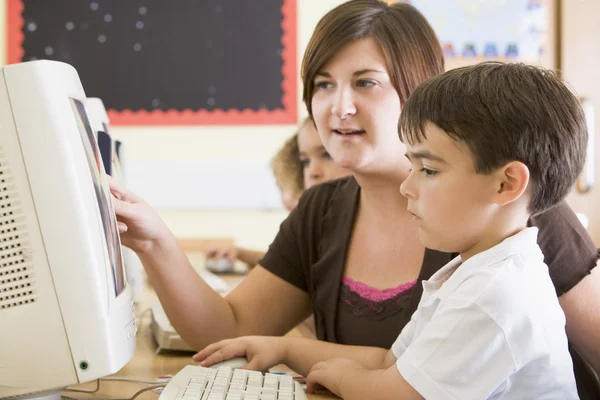 Um menino e seu professor trabalhando em um computador na escola primária — Fotografia de Stock