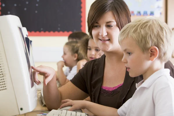 A boy and his teacher working on a computer at primary school — Stock Photo, Image