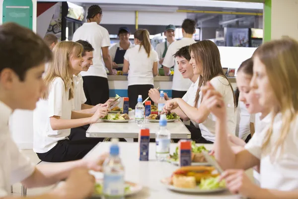 Estudiantes de secundaria comiendo en la cafetería de la escuela — Foto de Stock