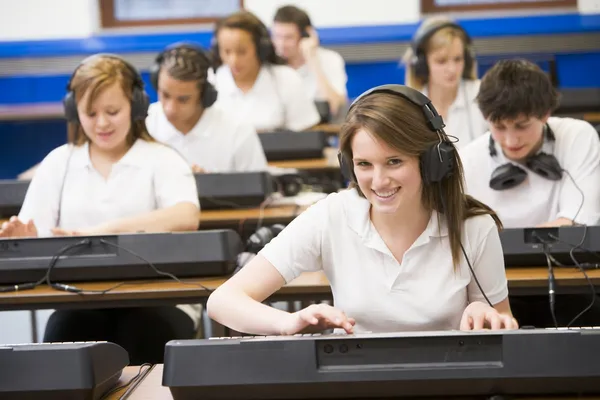 Crianças em idade escolar praticando em um teclado na aula de música — Fotografia de Stock