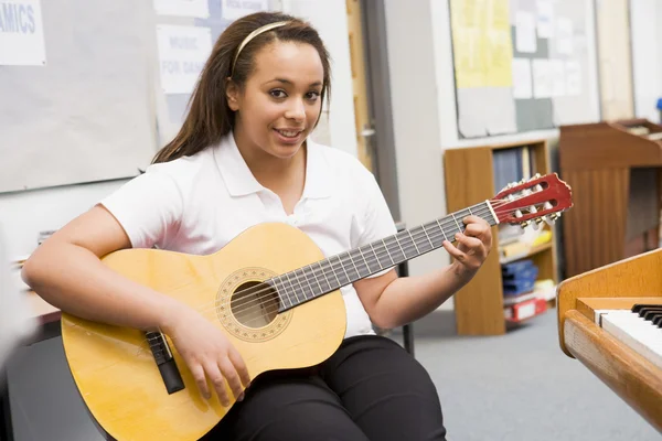 Schoolgirl playing guitar in music class — Stock Photo, Image
